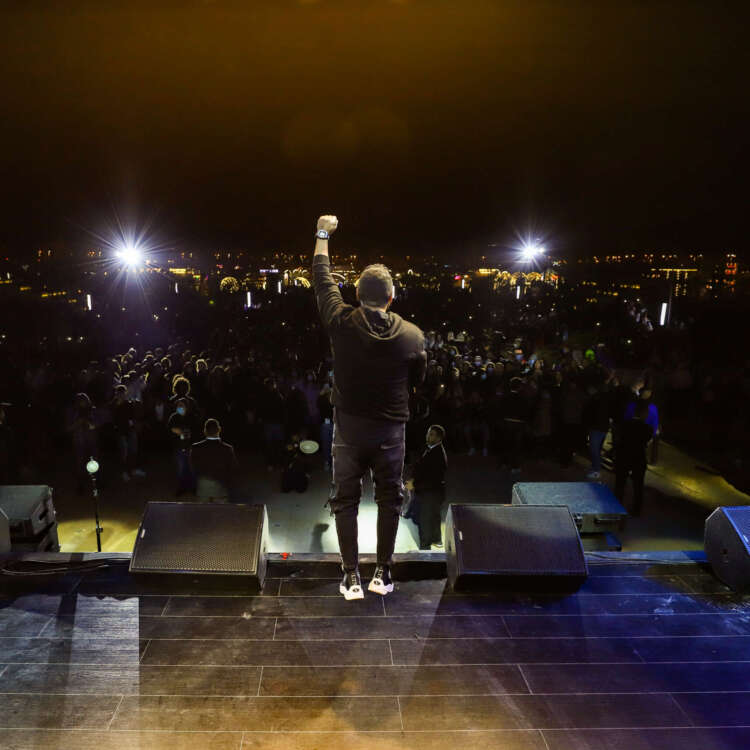 Tamer Hosny performing on stage during a Christmas event, captivating the audience with his music amidst festive decorations and lights.