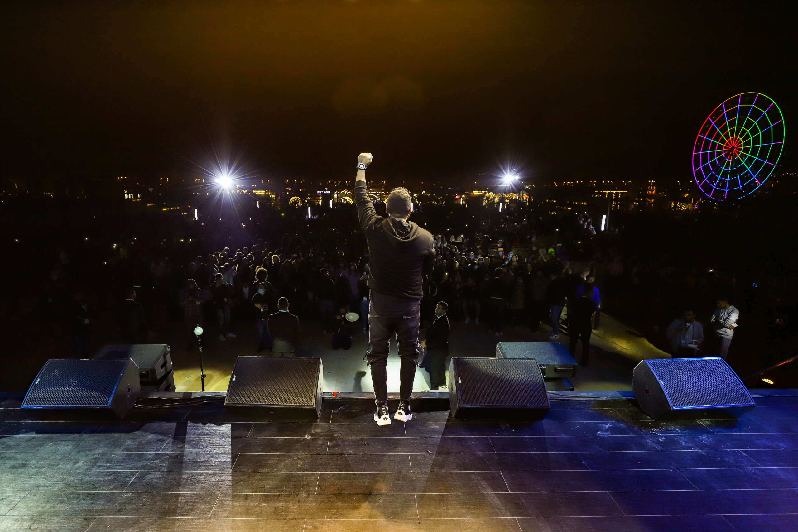 Tamer Hosny performing on stage during a Christmas event, captivating the audience with his music amidst festive decorations and lights.