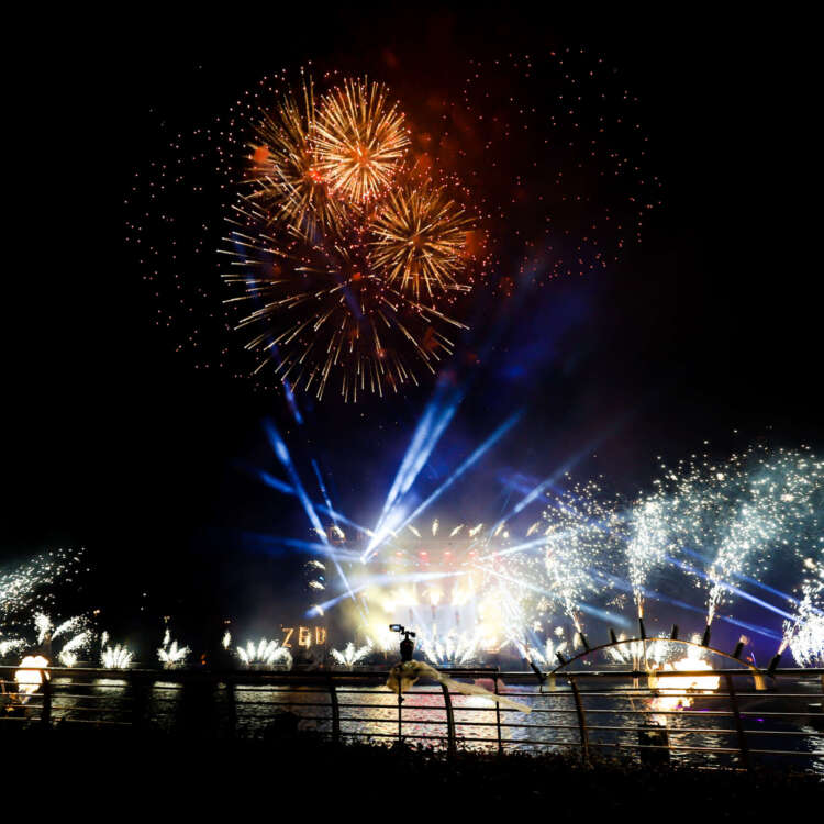 Fireworks lighting up the night sky over a festive Christmas scene, with colorful decorations and holiday lights