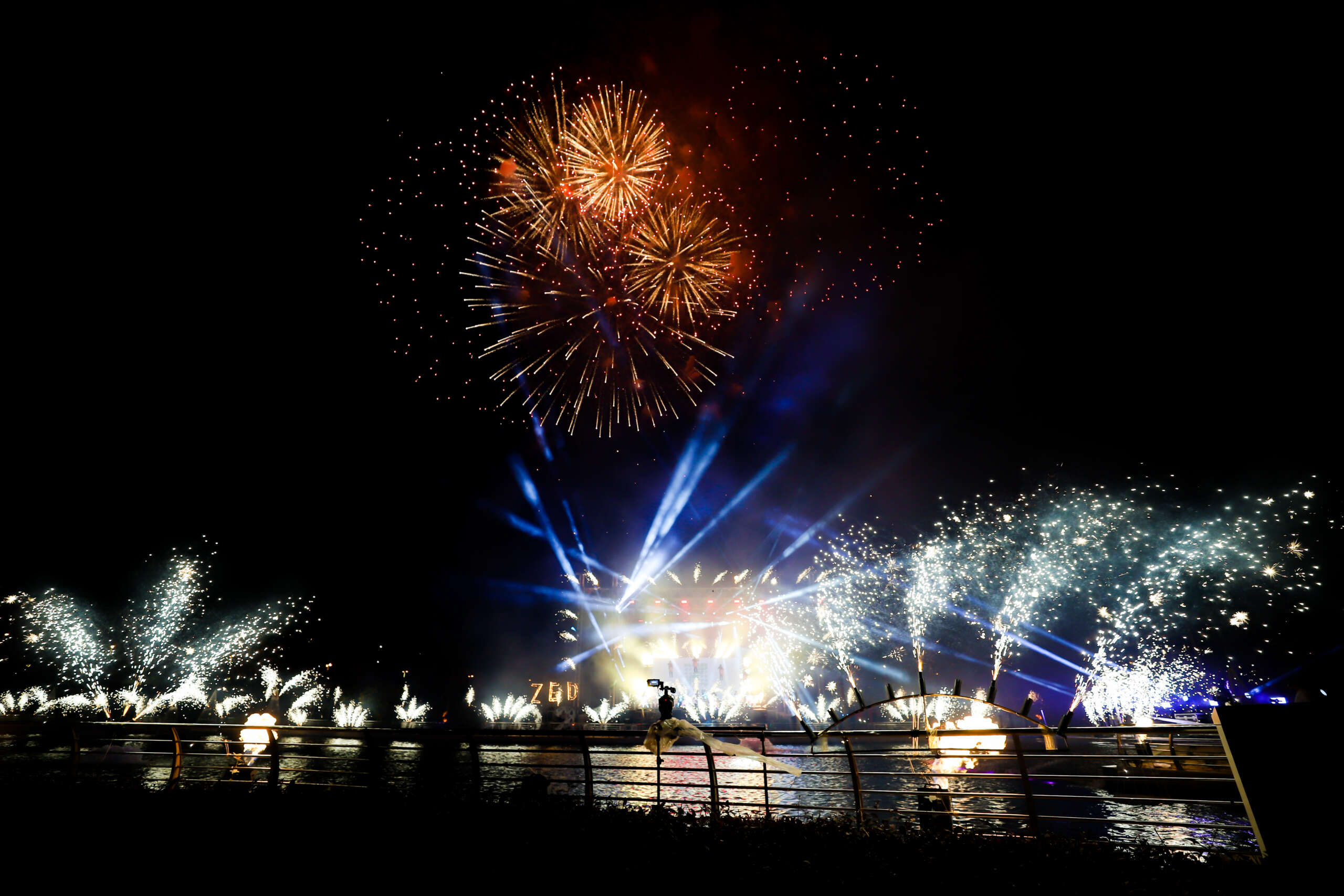 Fireworks lighting up the night sky over a festive Christmas scene, with colorful decorations and holiday lights