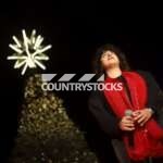 A girl singing in front of a Christmas tree adorned with lights and decorations, creating a festive holiday atmosphere.