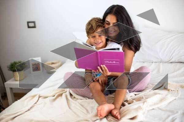 A girl is happily reading a book to her little brother