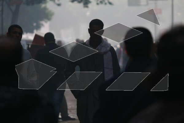 A young man in traditional Egyptian attire walks through a crowded.