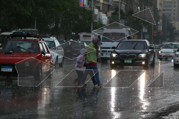 A woman and a child hurry across a busy street in Cairo, Egypt.