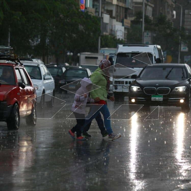 A woman and a child hurry across a busy street in Cairo, Egypt.