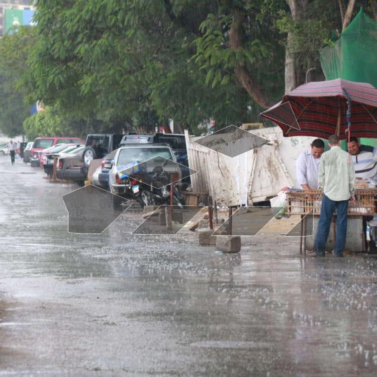 A rainy day in Cairo, Egypt, where two vendors stand under a large umbrella