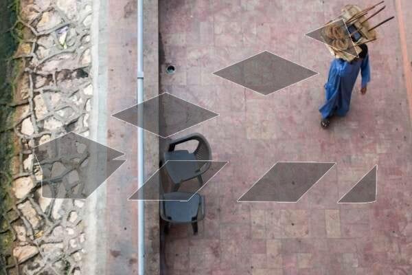 A street vendor in traditional blue attire walks along a tiled sidewalk in Egypt.