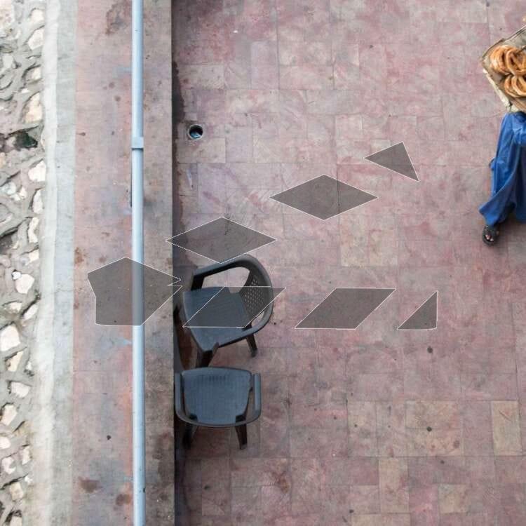 A street vendor in traditional blue attire walks along a tiled sidewalk in Egypt.