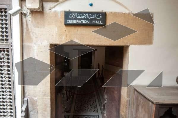 Exterior view of a traditional wooden door at the Gayer-Anderson Museum in Old Cairo, Egypt, with a sign above it reading ‘Banquet Hall’ in Arabic.