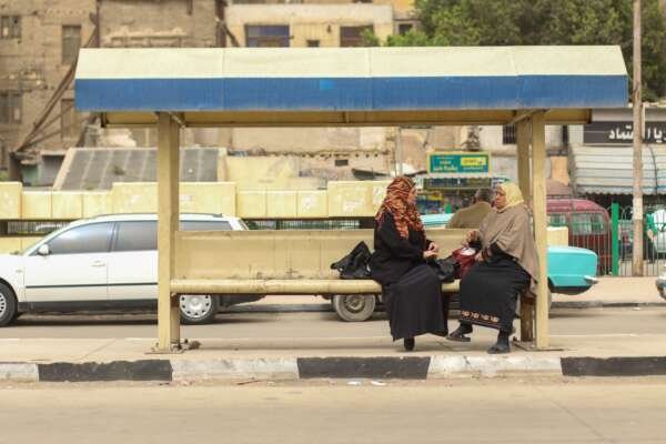 Two Women Sitting and Waiting for the Bus at a Station in Cairo