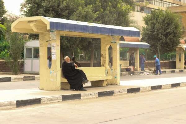 Man Sitting at Bus Station in Abbassia, Cairo, Holding a Cane