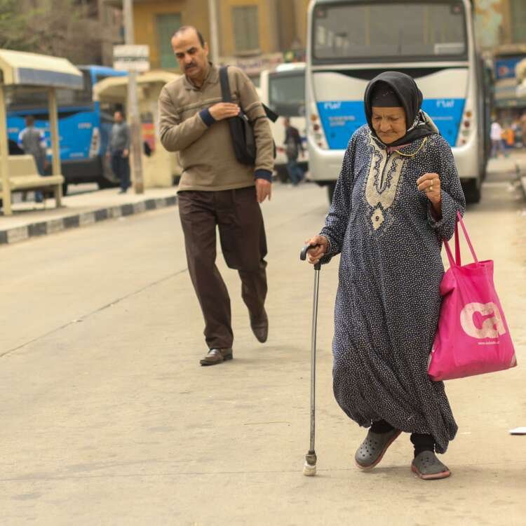 Woman Walking with a Cane Inside a Bus Station in Cairo