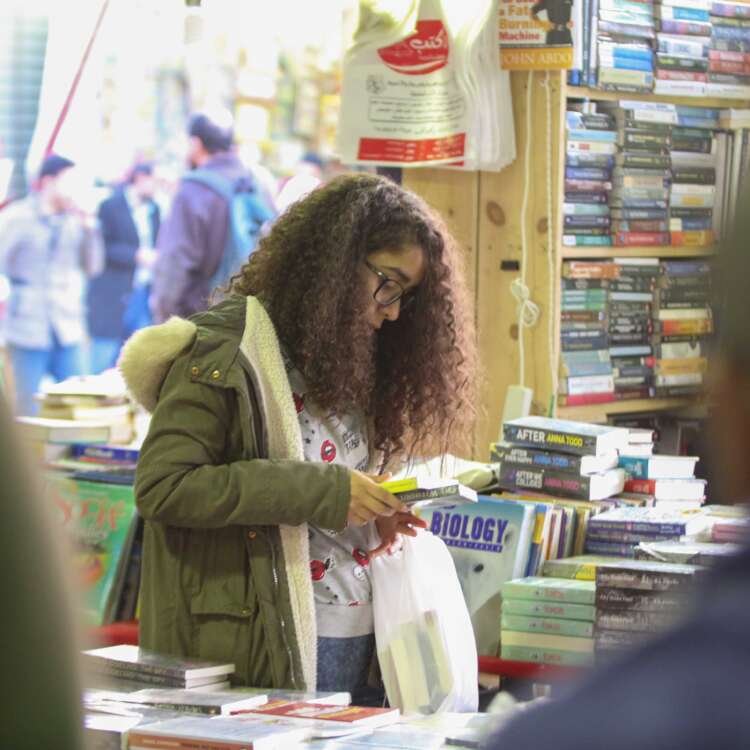 Curly-Haired Girl Reading a Book at Cairo International Book Fair – 2017