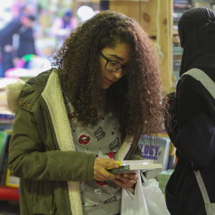 Curly-Haired Girl Reading a Book at Cairo International Book Fair – 2017
