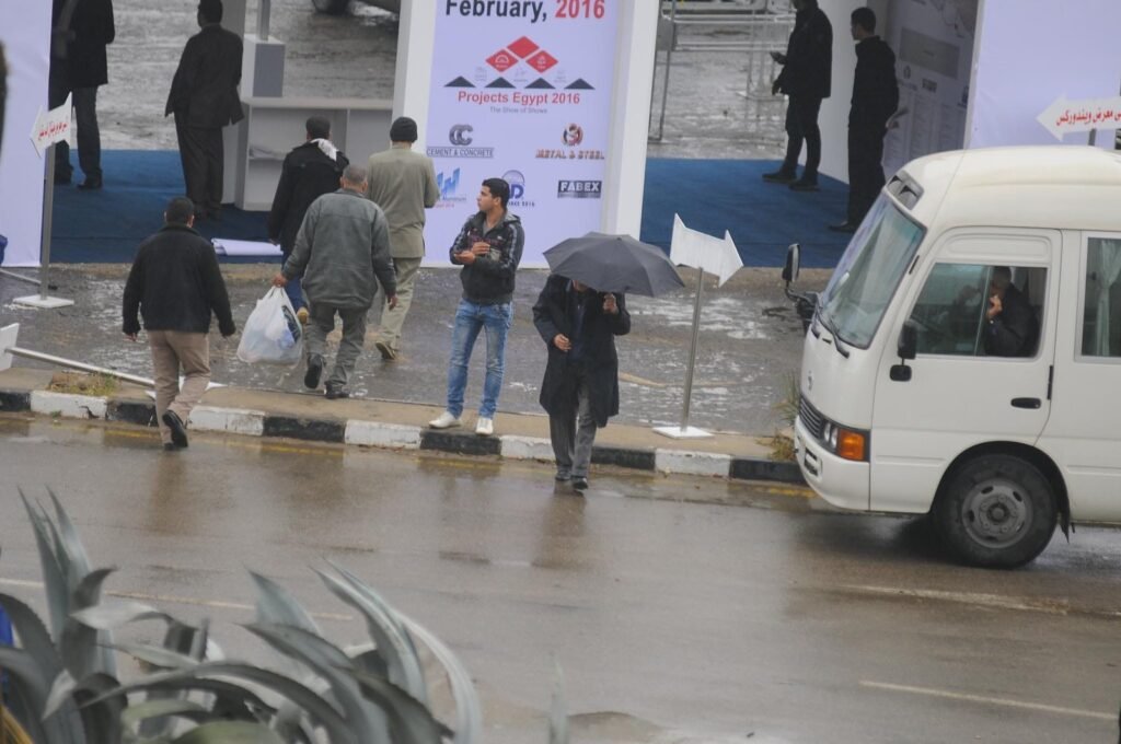 
									Rainy Street Scene with Umbrella and MiniBus in Cairo