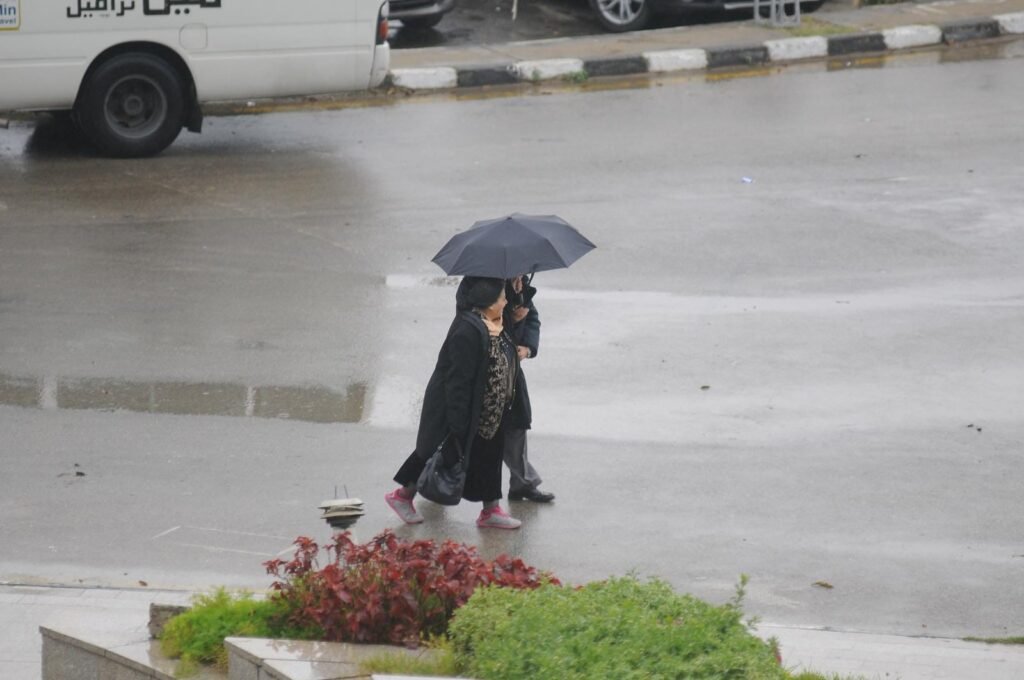 
									Woman and Man Walking with Umbrella on Rainy Cairo Street