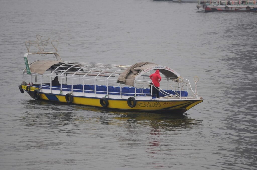A boat in the middle of the Nile with a woman standing on it, enjoying the view of the river and the surrounding cityscape.