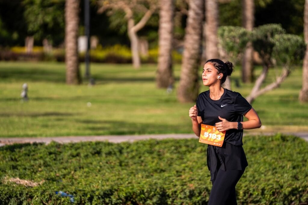 A woman takes part in the Madinaty Marathon, running with energy and determination.