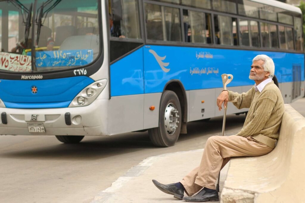 Man Sitting at Bus Station in Abbassia, Cairo, Holding a Cane