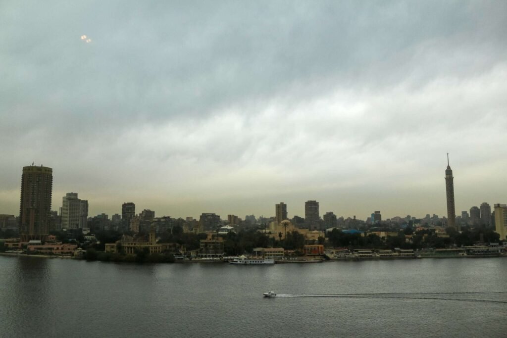 Boat on the Nile with Cloudy Sky, Cairo Skyline, and Cairo Tower