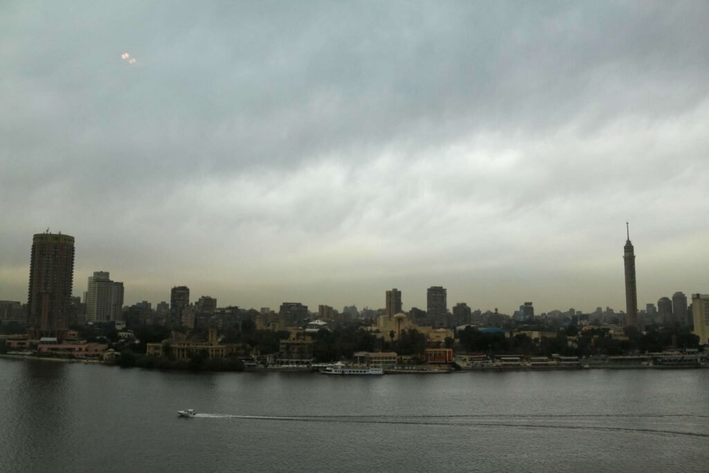Boat on the Nile with Cloudy Sky, Cairo Skyline, and Cairo Tower