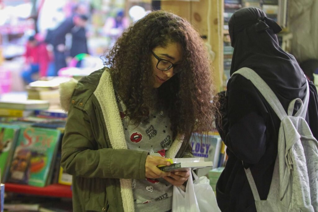 Curly-Haired Girl Reading a Book at Cairo International Book Fair – 2017