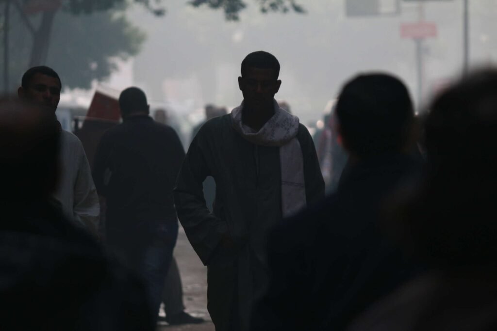 A young man in traditional Egyptian attire walks through a crowded