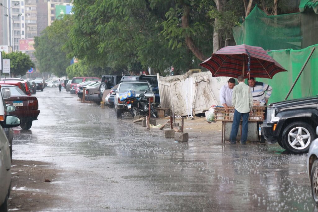 A rainy day in Cairo, Egypt, where two vendors stand under a large umbrella