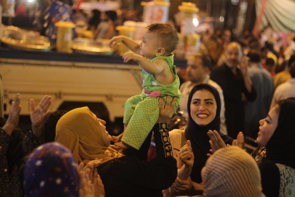 Women Carrying Children on Their Shoulders During Festive Mawlid Celebration – Cairo, Egypt