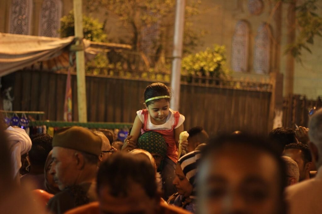 Women Carrying Children on Their Shoulders During Festive Mawlid Celebration – Cairo, Egypt