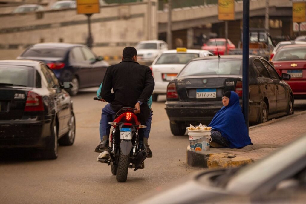 Motorcycle Rider Passing Street Vendor in Cairo