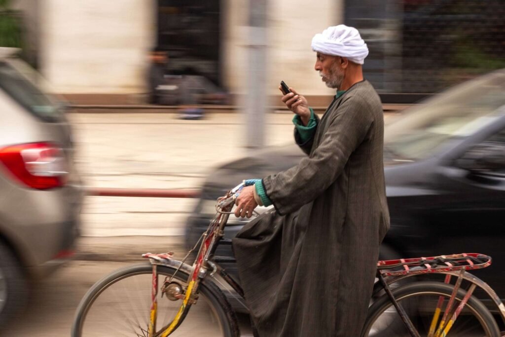 Saidi Man Riding a Bicycle While Using a Mobile Phone in Cairo