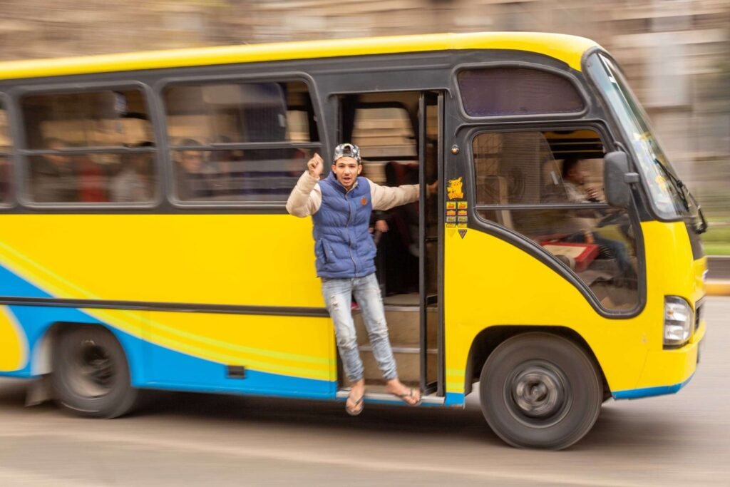 Young Man Hanging from Moving Minibus in Cairo