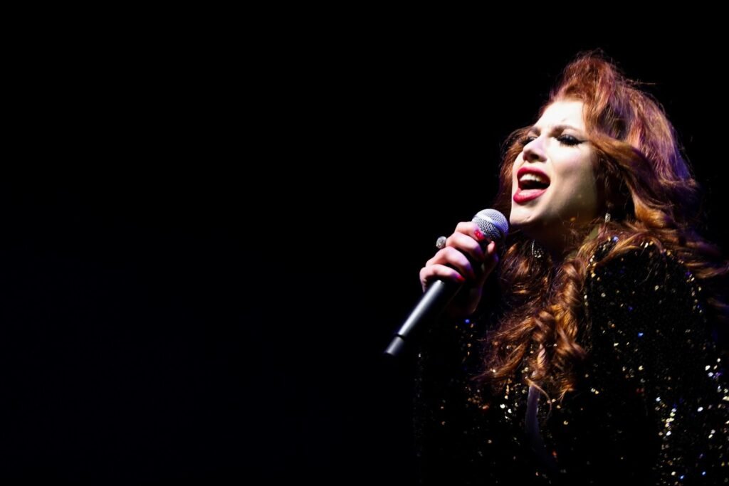 A girl singing in front of a Christmas tree adorned with lights and decorations, creating a festive holiday atmosphere